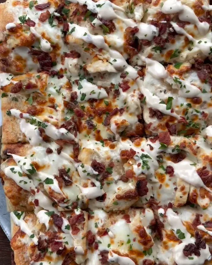 Overhead view of this week's square sourdough pizza: chicken, crispy bacon, an Alfredo drizzle and chopped parsley